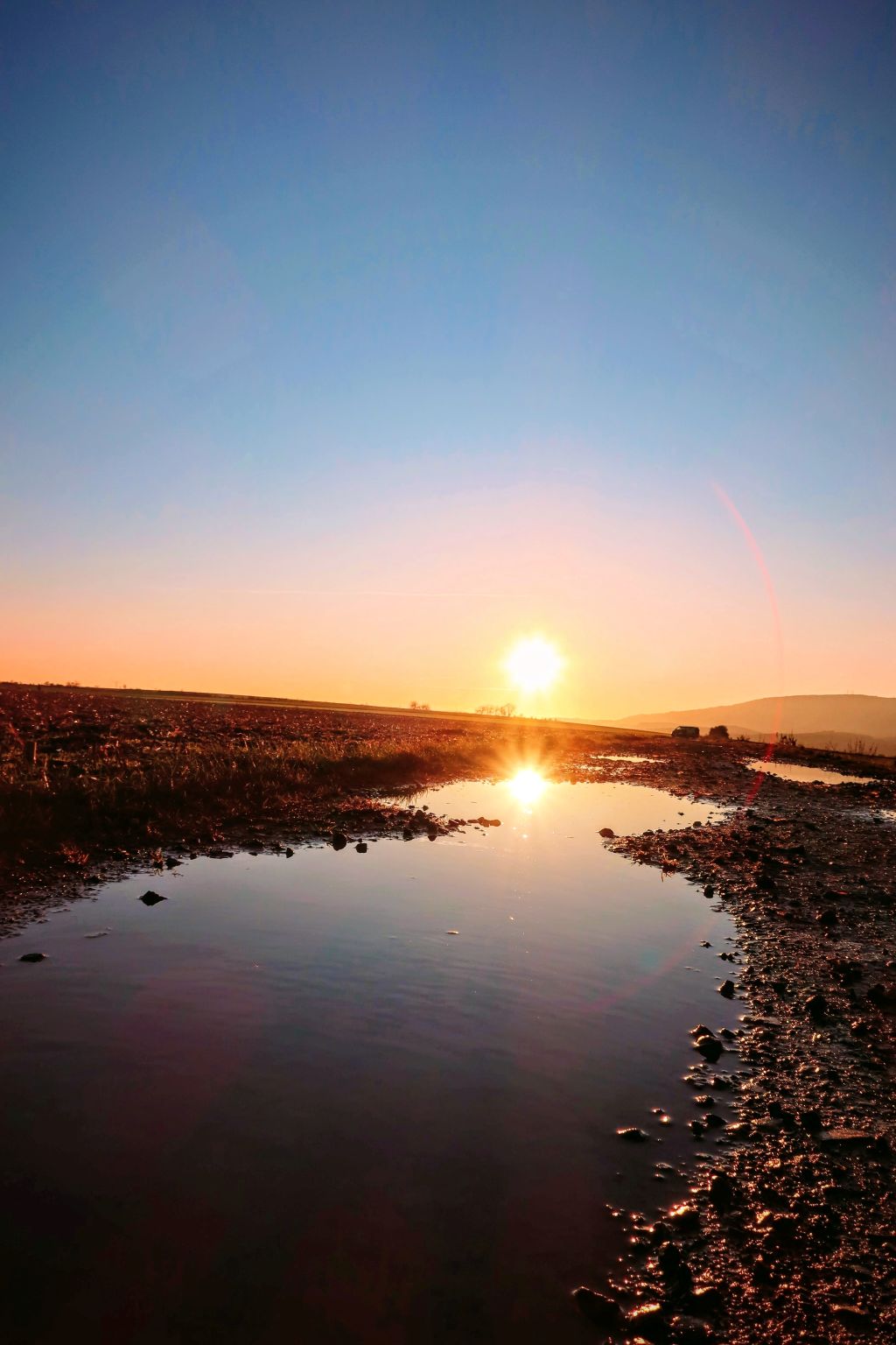 Sonnenuntergang auf dem Hungerberg mit Wasserpfütze und Spiegelung